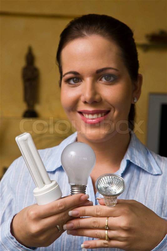 Woman changes in energy-saving light bulb lamp, stock photo