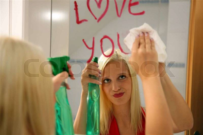 Young woman drops a sweet message on the mirror in the bathroom, stock photo