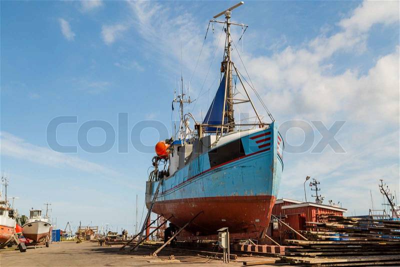 Medium-sized fishing boat standing in a drydock for repairs, stock photo