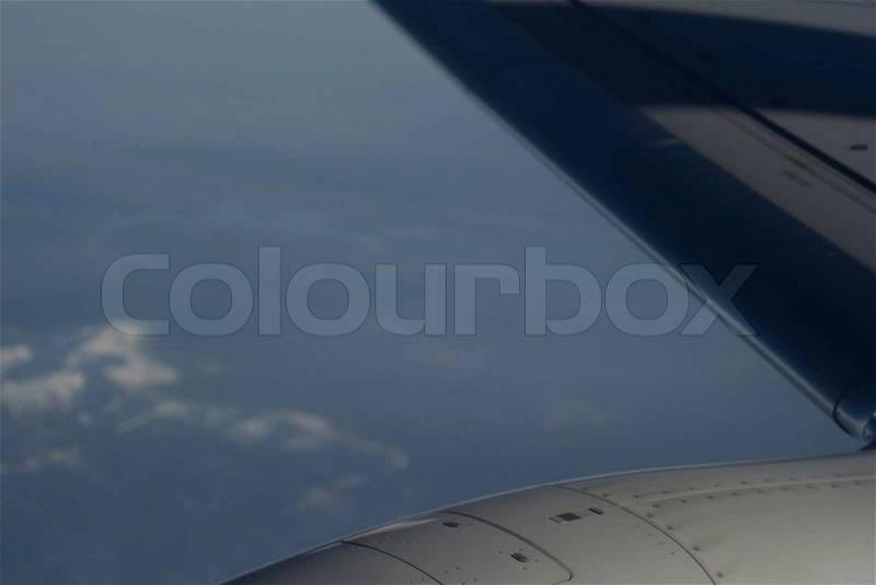 Airplane flying in sky over land in flight engine wing, stock photo