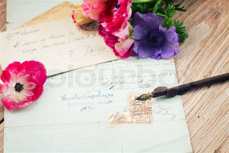 Old retro golden quill pen and antique testament with anemone flowers, stock photo