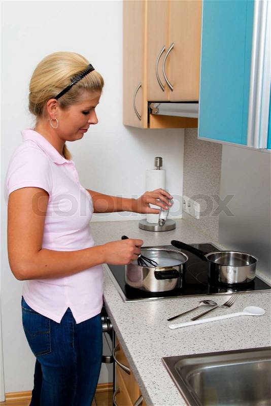 A woman in the kitchen while cooking with electric stove, stock photo