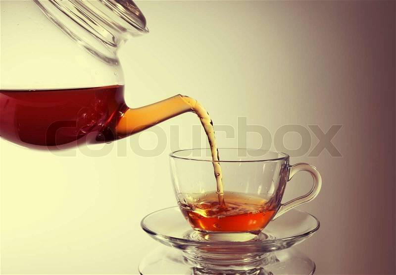 Pouring tea to a teacup, stock photo