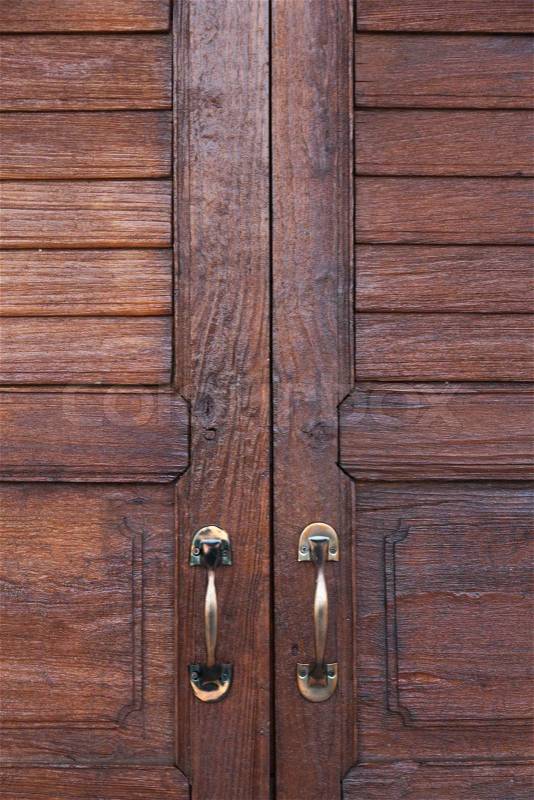 Door handle. Brown wooden door. The door handle is aluminum, stock photo