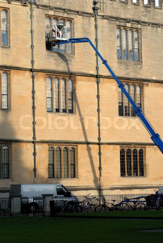 Window cleaner working on windows in collage building in Oxford, Oxfordshire, England, stock photo