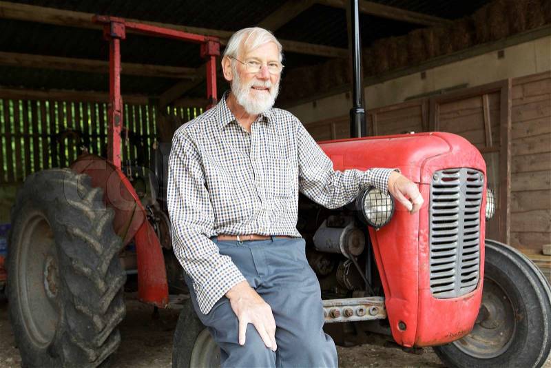 Organic Farmer Sitting Next To Old Fashioned Tractor, stock photo