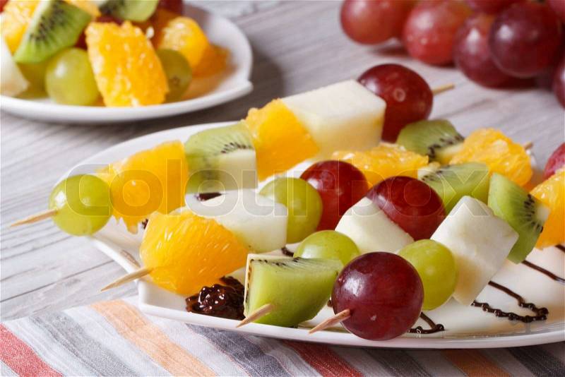 Fresh fruit on skewers on a white plate close-up. horizontal , stock photo