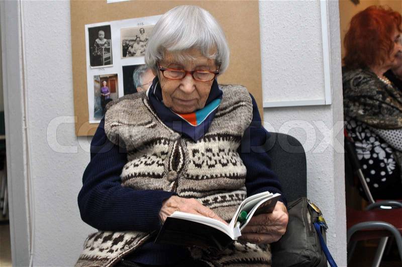 An old woman reading a book in medical center, stock photo
