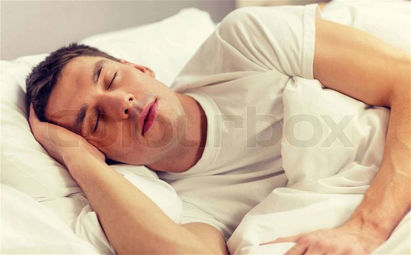 Hotel, travel and happiness concept - handsome man sleeping in bed, stock photo