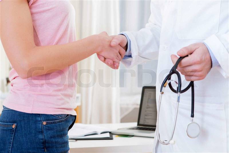 View of a Young attractive doctor shaking hand of his patient, stock photo