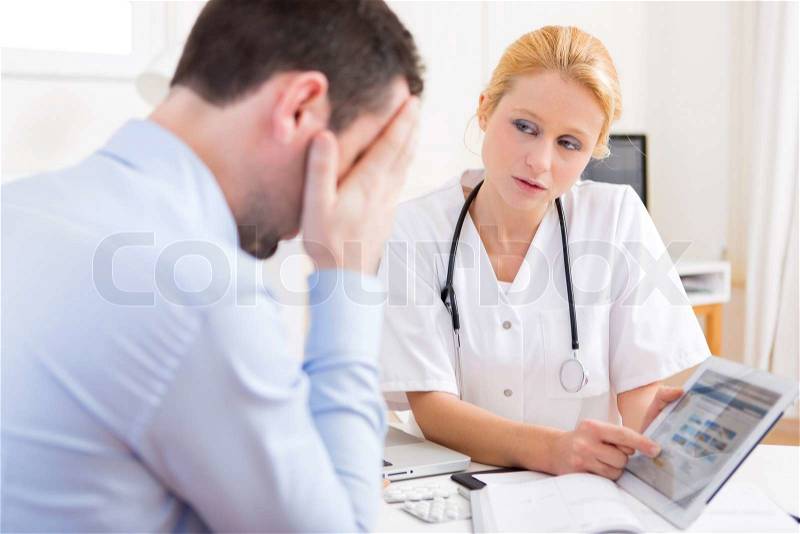 View of a Young doctor showing results on tablet to patient, stock photo
