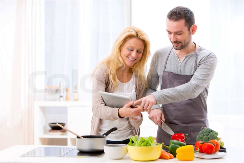 View of a Young attractive couple reading recipe on a tablet, stock photo