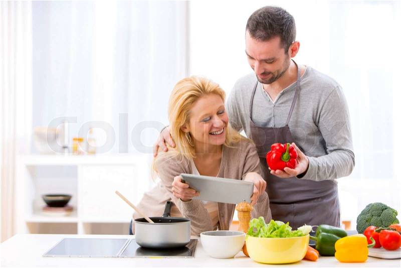 View of a Young attractive couple reading recipe on a tablet, stock photo