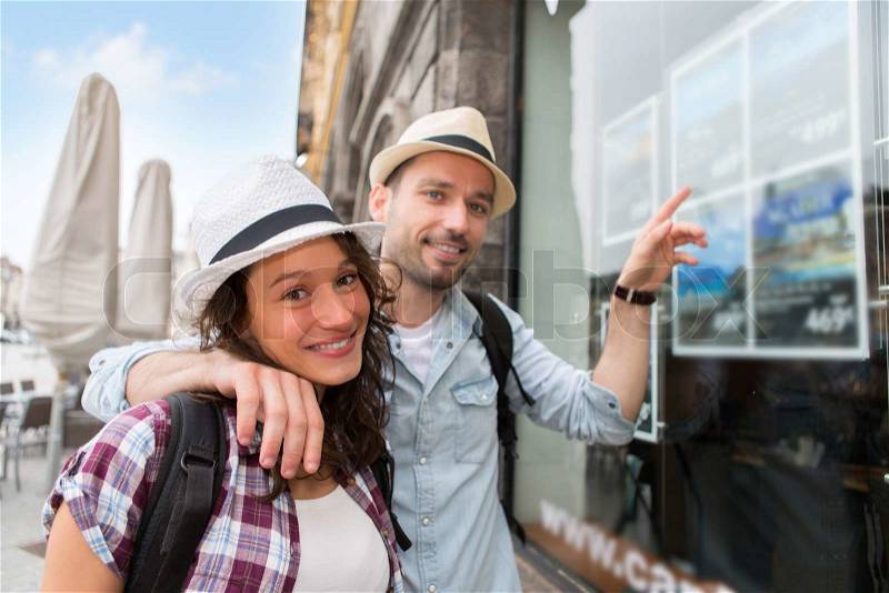 View of a Young happy couple in front of travel agency, stock photo
