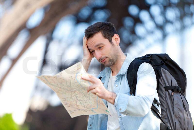 Young attractive tourist reading map in Paris, France, stock photo