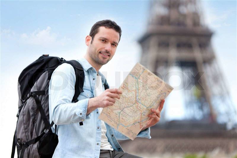 Young attractive tourist reading map in Paris, France, stock photo