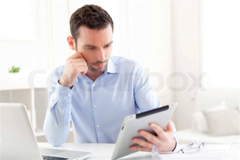 View of a Young business man working at home on his tablet, stock photo