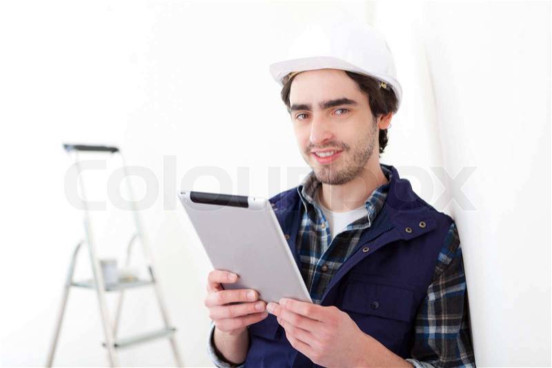 View of a Young worker man in a new flat using tablet, stock photo