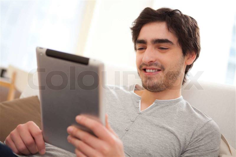 Portrait of a young relaxed men in a sofa using tablet, stock photo