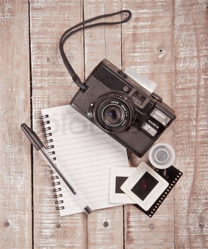 Old camera and film with diary on a wooden,vintage color toned image, stock photo