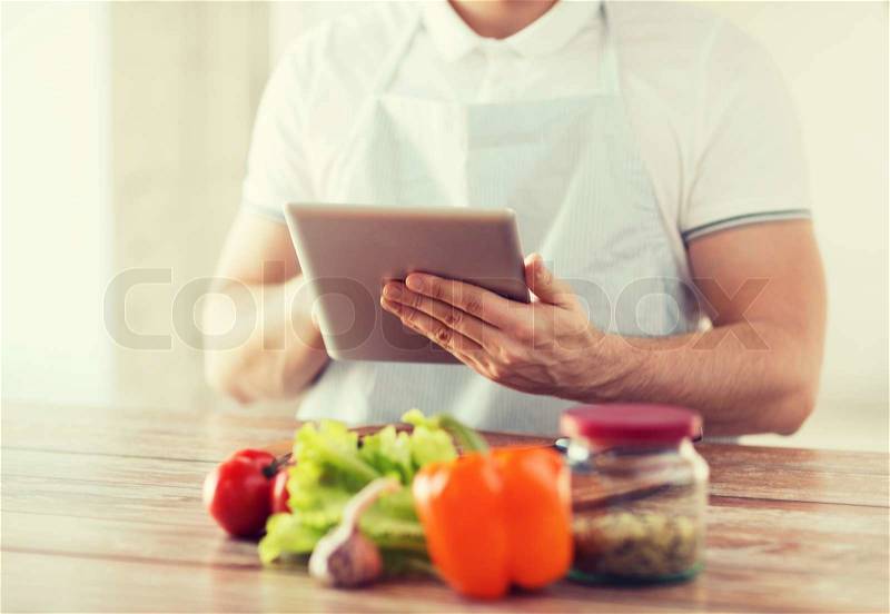 Cooking, technology and home concept - closeup of man reading recipe from tablet pc computer, stock photo