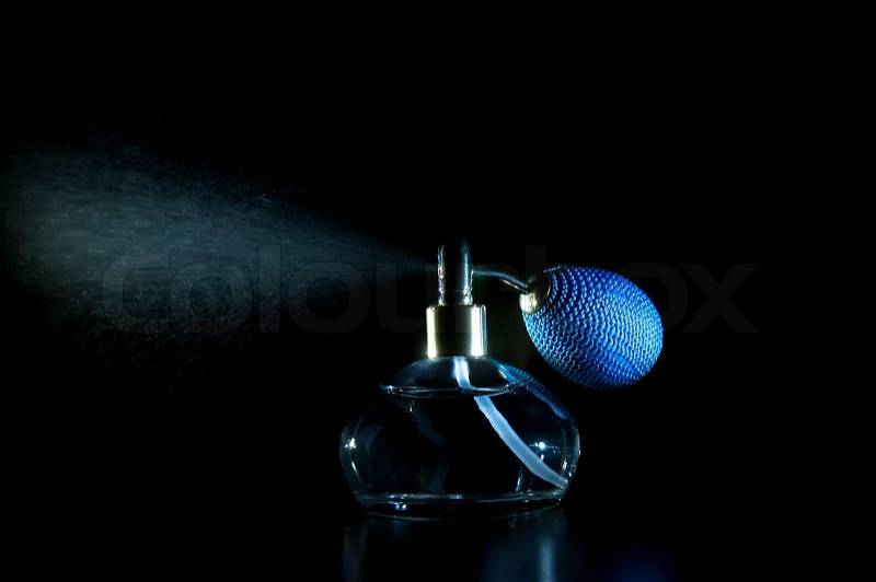 Vintage antique perfume bottle with effect of perfume spray on black background, stock photo