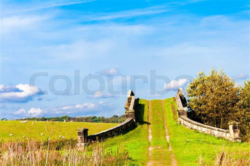 English countryside landscape with grazing sheep and old bridge, stock photo