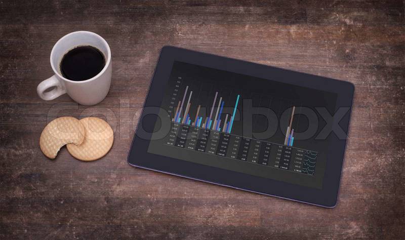 Tablet touch computer gadget on wooden table, graph, vintage look, stock photo