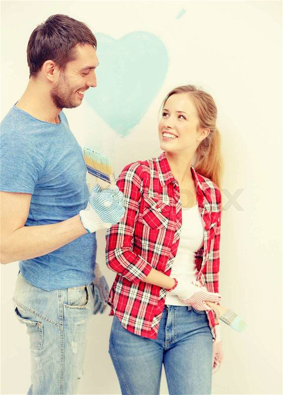 Repair, building and home concept - smiling couple painting small heart on wall at home, stock photo