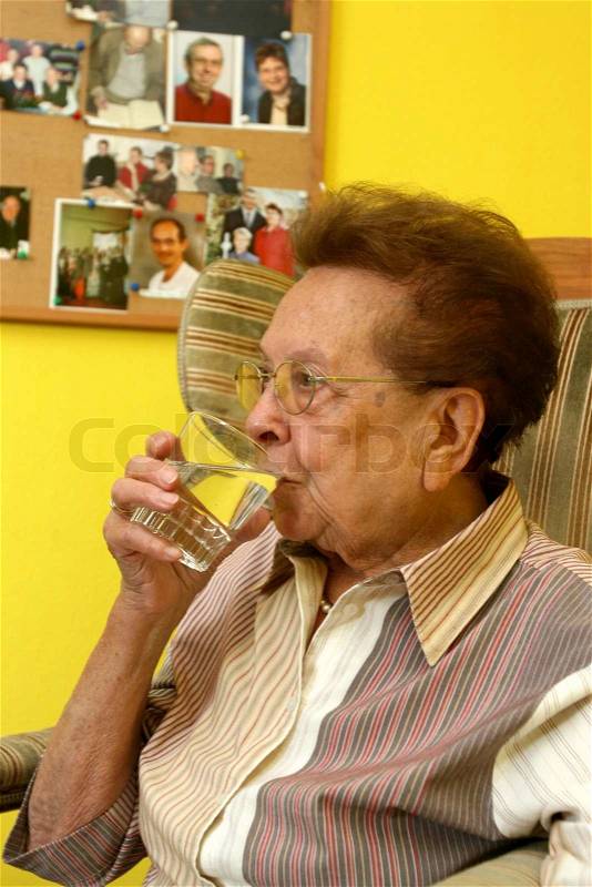 An elderly woman drinking a glass of water, stock photo