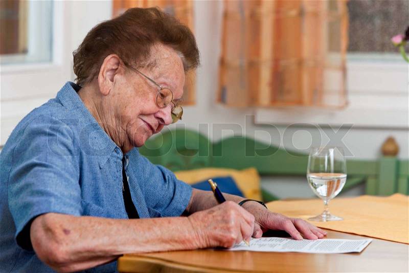 An old woman signs a contract, stock photo