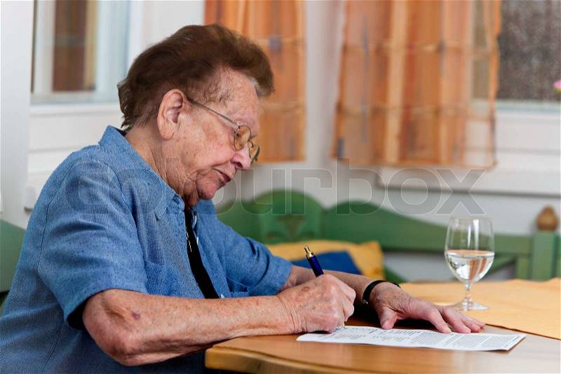An old woman signs a contract, stock photo