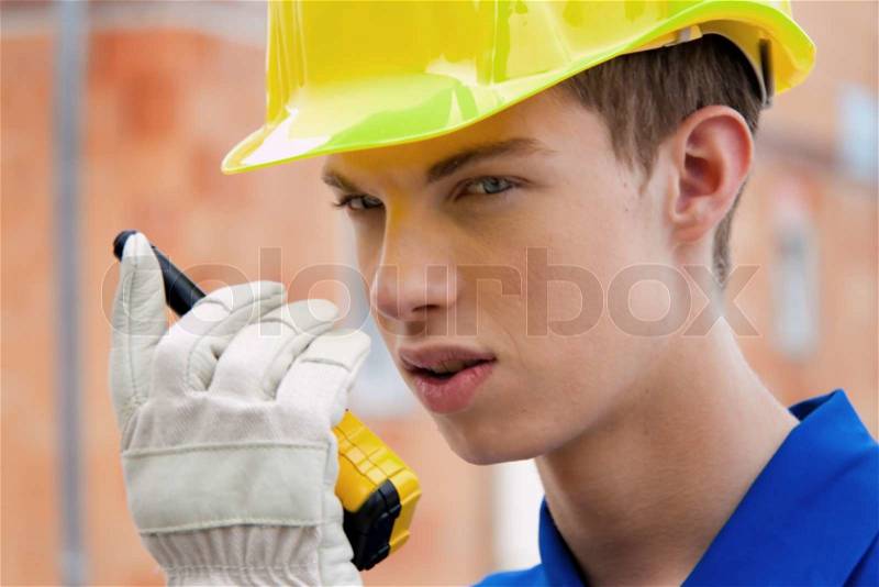 An apprentice / trainee. Construction workers on site with a helmet, stock photo
