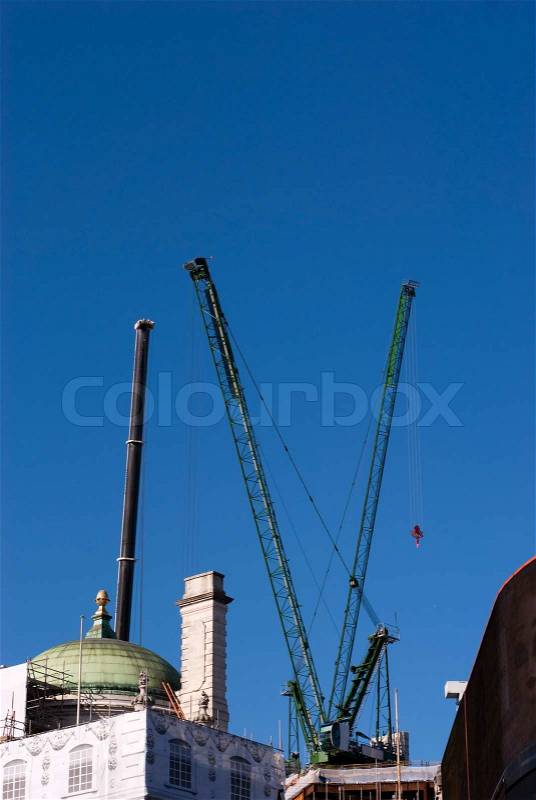 Vertical construction cranes with copy space outdoors and sky blue in London, England, stock photo