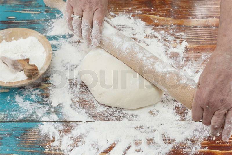 Baking. Woman rolling out pastry with a rolling pin on floured surface. Copy space for your text, stock photo