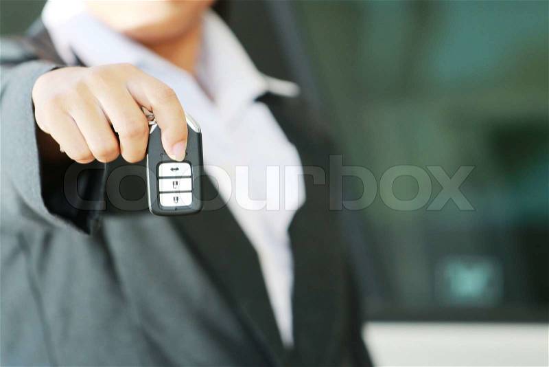 Business woman show a remote car key and operate. car background, stock photo