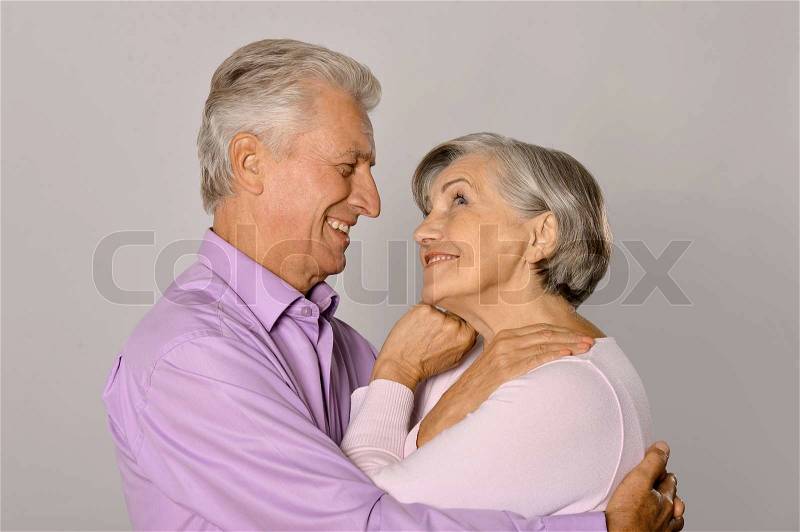 Happy older pair on a gray background, stock photo