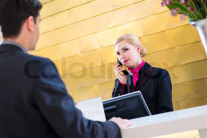 Hotel receptionist telephoning with guest for reservation or information , stock photo