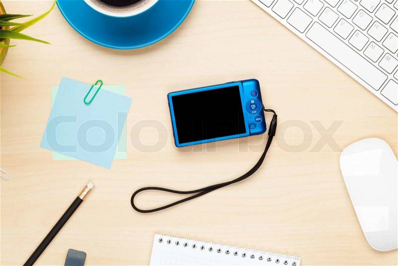 Photo camera on office table with notepad, computer and coffee cup. View from above, stock photo
