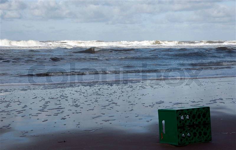 Beer crate on the beach with high waves on the water, stock photo