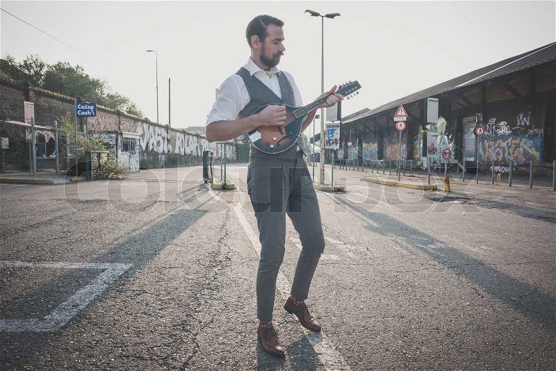 Handsome big moustache hipster man playing mandolin in the city, stock photo