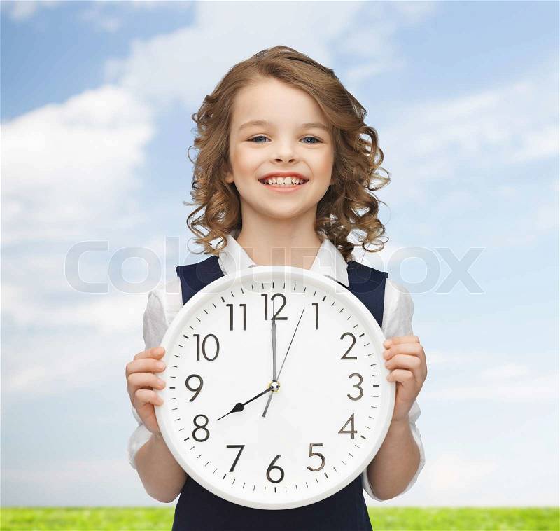 People, time management and children concept - smiling girl holding big clock showing 8 o\'clock, stock photo