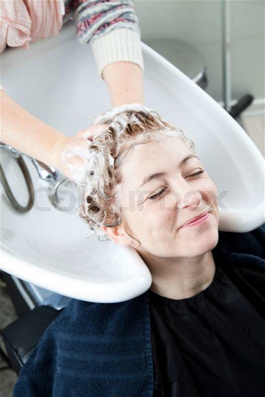 A woman getting her hair washed in a hair salon, stock photo
