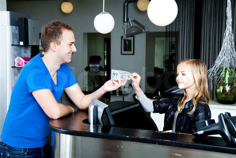 A man paying a young girl in a beauty parlor, stock photo
