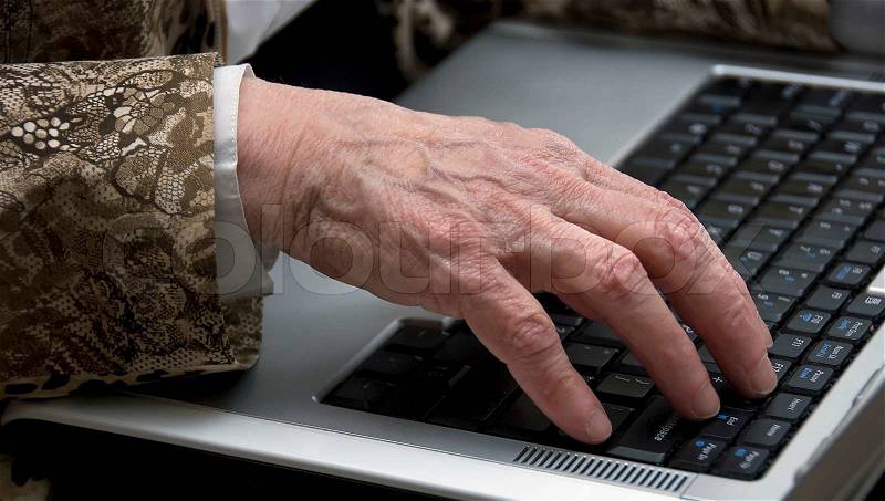 Hand of a woman older then 80 , working on a mobile laptop, stock photo