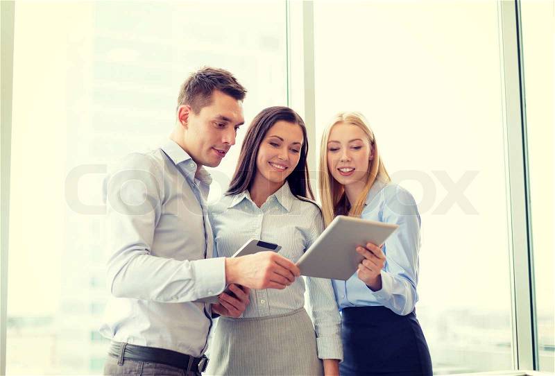 Business and office concept - smiling business team working with tablet pcs in office, stock photo