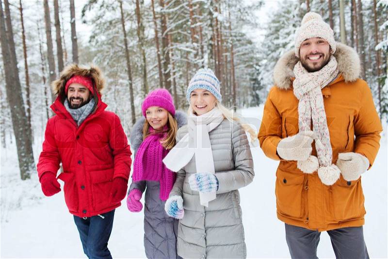 Love, relationship, season, friendship and people concept - group of smiling men and women running in winter forest, stock photo