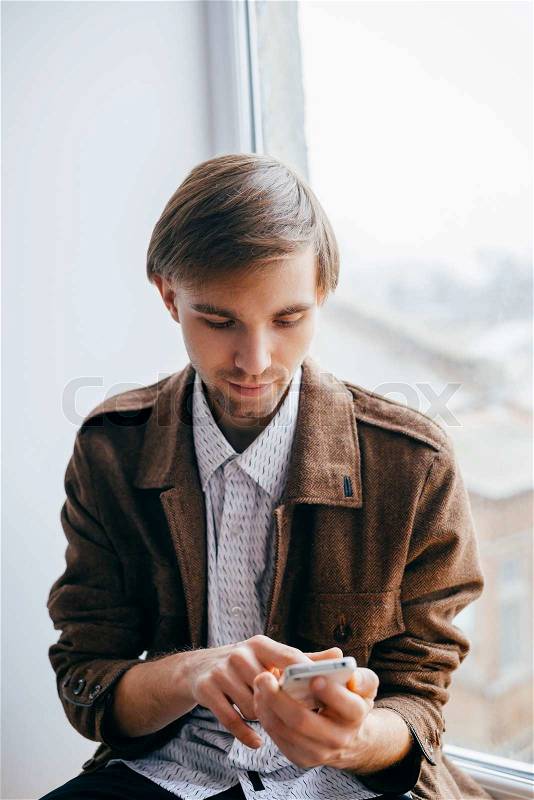 Young man dials number on mobile phone, stock photo