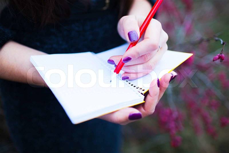 Girl on nature writing in a notebook, stock photo