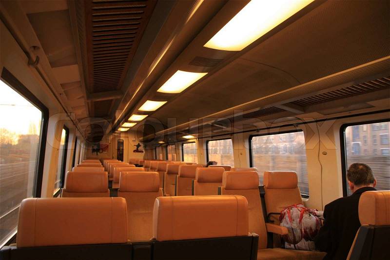 The solitary man sits in the compartment of the train to Amsterdam by sunrise, stock photo